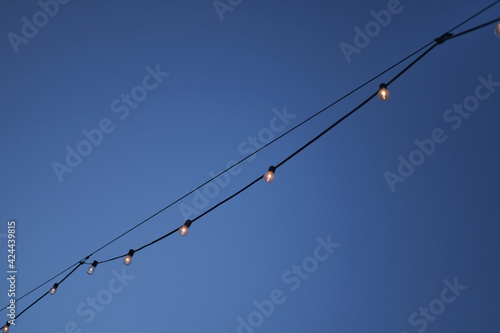 An isolated string of seaside fairy lights against a clear blue dusk sky