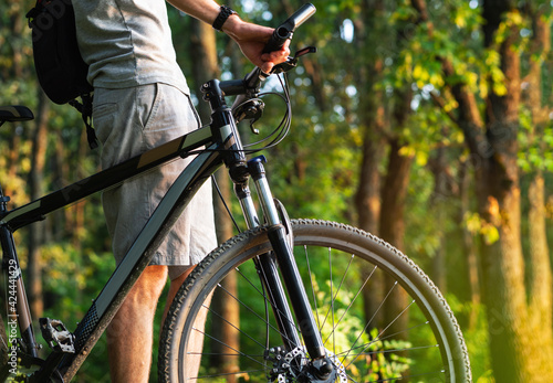 Close-up of a cyclist and a bicycle in a green sunny park. Summer time and the concept of an active lifestyle.
