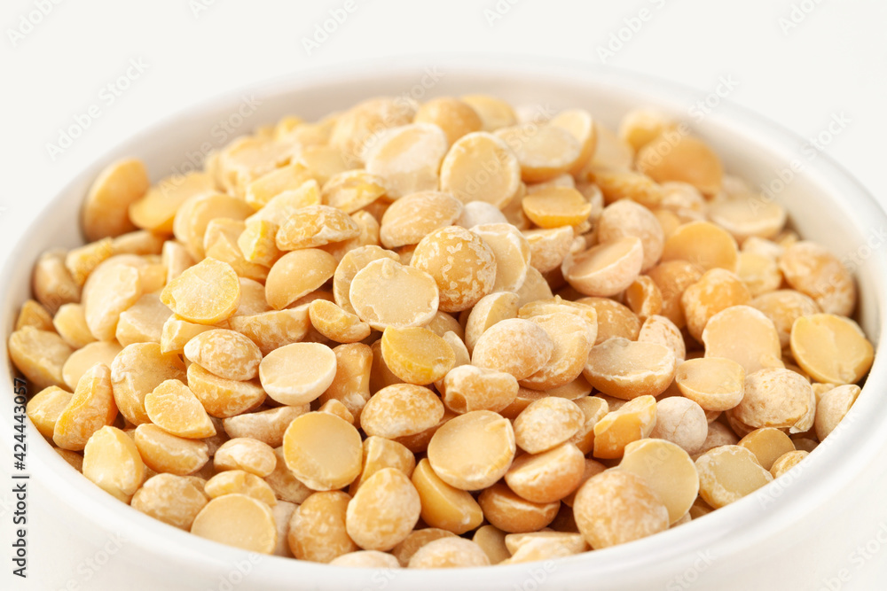 Raw dried uncooked pea beans with white ceramic bowl macro Raw dried uncooked pea beans with white ceramic bowl macro