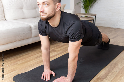 sport, fitness and healthy lifestyle concept - man doing plank exercise at home. workout abs, stability body, man training tricep pushups. © Julija