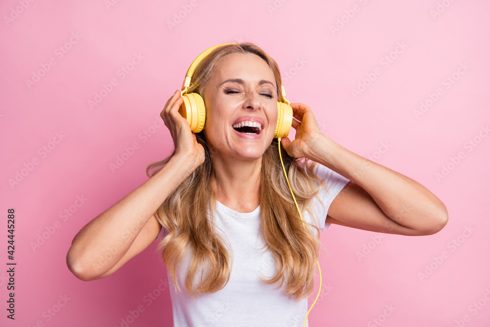 Photo of cool optimistic blond lady closed eyes listen music wear white t-shirt isolated on pastel pink color background Photo of cool optimistic blond lady closed eyes listen music wear white t-shirt isolated on pastel pink color background