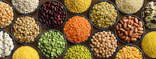 Various colorful legumes and cereals in black bowls background. photo