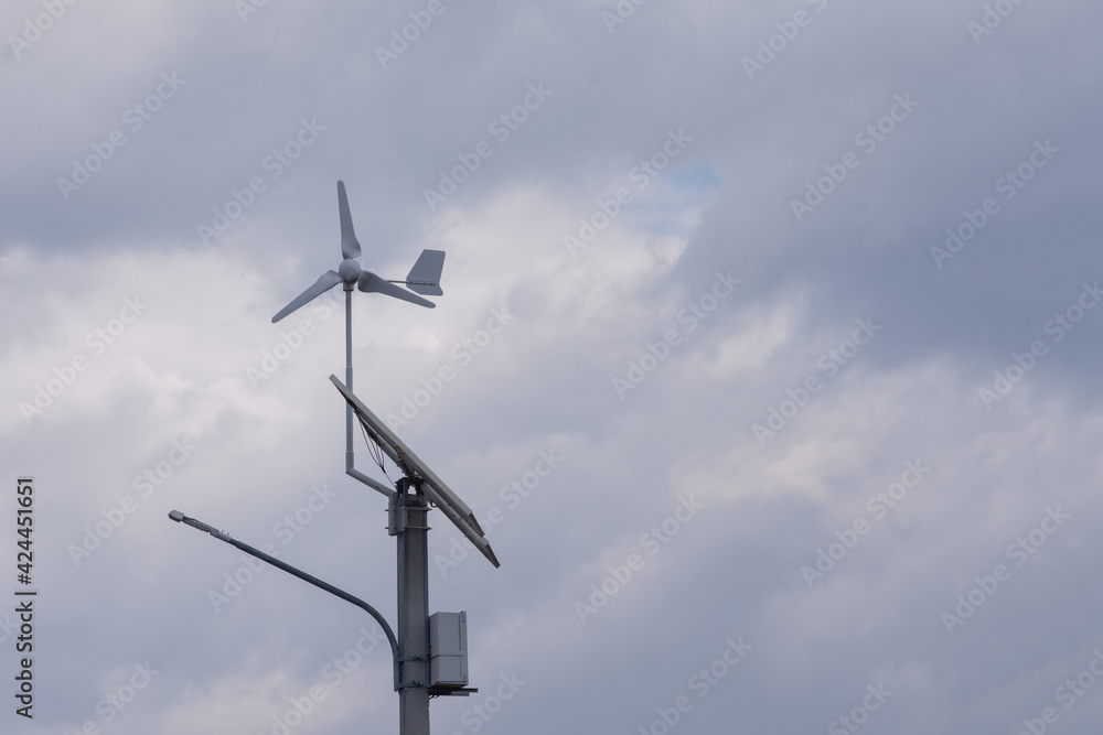 Wind turbine and solar battery, small kit for street lighting. Against the background of clouds Wind turbine and solar battery, small kit for street lighting. Against the background of clouds