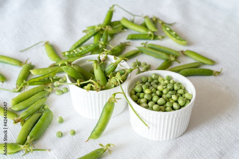 Fresh green peas decoration on a white textile background, top view Fresh green peas decoration on a white textile background, top view