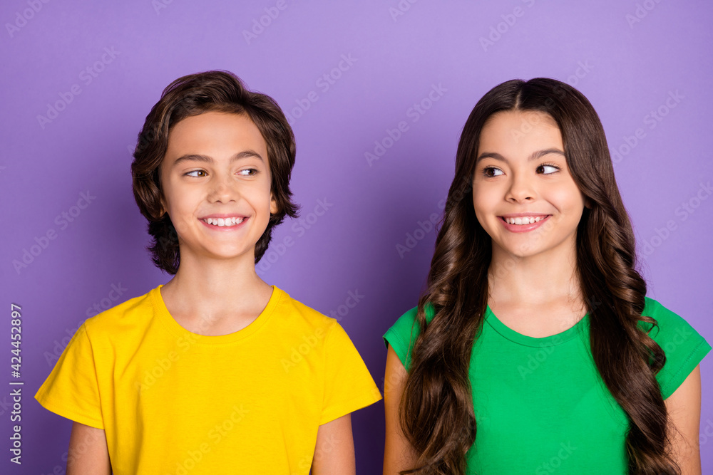 Photo of two preteen kids girl boy happy positive smile look each others isolated over purple color background Photo of two preteen kids girl boy happy positive smile look each others isolated over purple color background