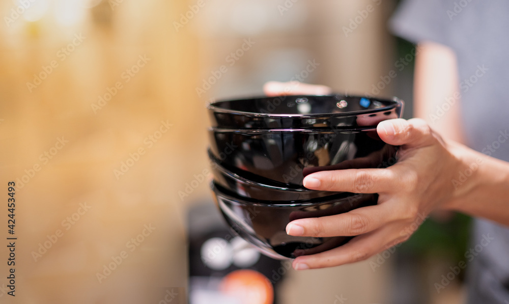 Female hand holding the stack of bowl, for keeping on the shelf. Female hand holding the stack of bowl, for keeping on the shelf.