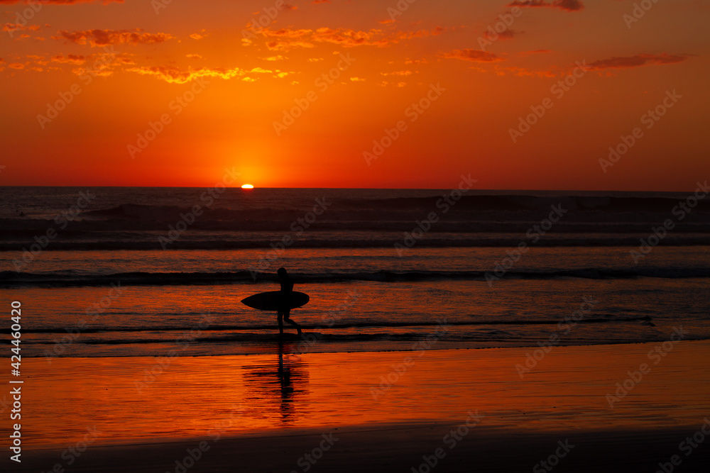 silhouette of a surfer at sunset on beach