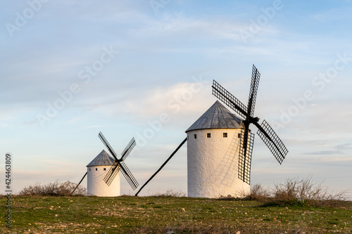 two whitewashed traditional Spanish windmills on the plains of La Mancha