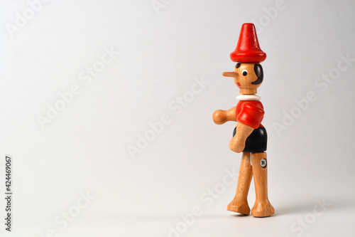 Obraz na plátne Wooden puppet depicting Pinocchio walking on a white background