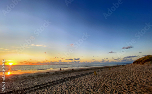 View of the setting sun shining on the Sea and reflected on the beach  clouds with sun-shining edges. Landscape. High quality photo