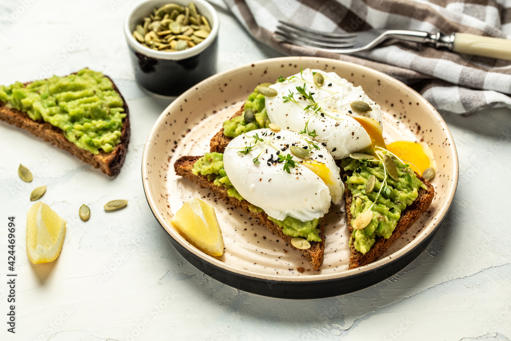 Sandwich with avocado and poached egg on whole wheat toasted bread. Food recipe background. Close up