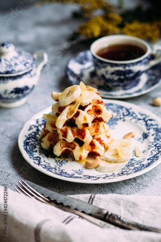 Belgian waffles with banana and honey on a vintage blue plate © elenavah