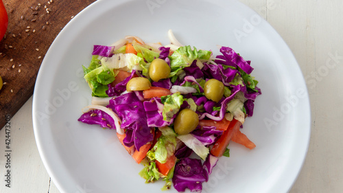 Flat lay view of a fresh mediterranean style salad, placed on top of a white table