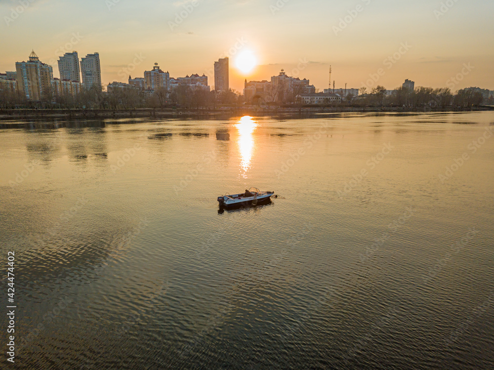 Naklejka premium Fishing boat on the water in the rays of the sunset. Aerial drone view.