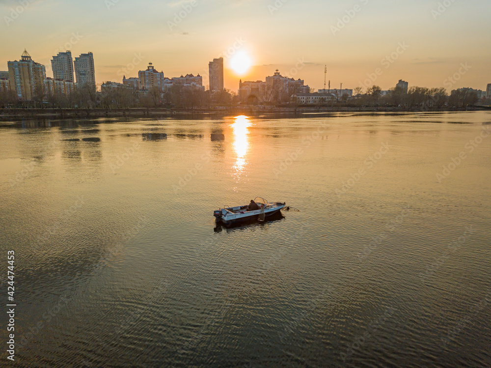 Fishing boat on the water in the rays of the sunset. Aerial drone view.