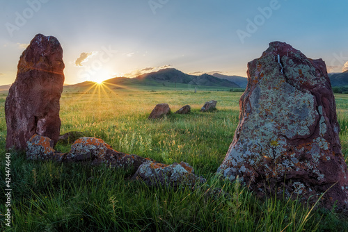 View of the ancient burial mounds and menhirs in the steppes and mountains of Khakassia near Kazanovka with sunbeams