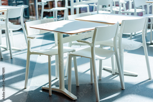White tables and square-shaped chairs in the lighted dining room. Close up. Nobody © _KUBE_