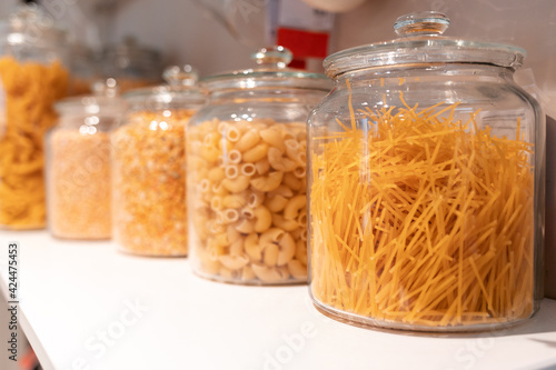 Cuisine and food. A row of glass jars with different types of pasta. Close up