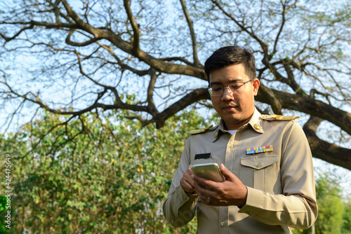 A Thai government officer, Civil servant is using his smartphone outdoors.