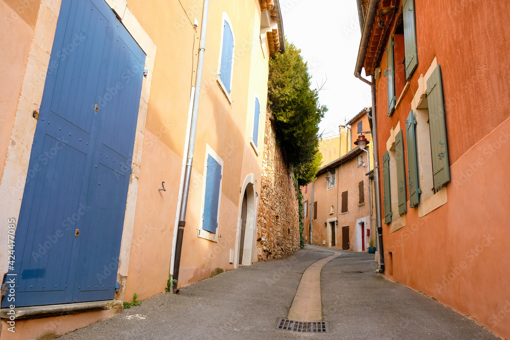Empty narrow street of the Provencal village. Old houses painted with ocher. Street water drainage. Roussillon tourist village. France. Empty narrow street of the Provencal village. Old houses painted with ocher. Street water drainage. Roussillon tourist village. France.