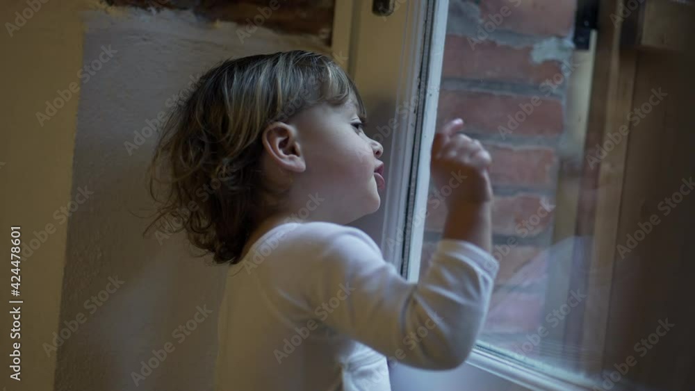 Child boy standing by window pointing at something outside Child boy standing by window pointing at something outside