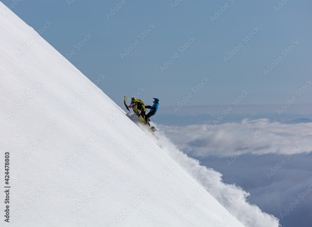 snowmobiler rides to the top of a steep wall-above the clouds. flying to the peak of the mountain on a turbocharged snowmobile. copy space. high resolution photo