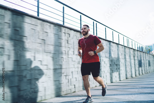 Determined sportsman running and listening to music with earphones