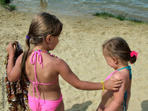 Two little girls  on a sandy beach by the river
