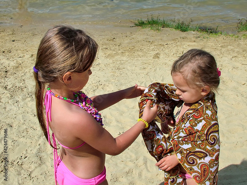 Two little girls on a sandy beach by the river