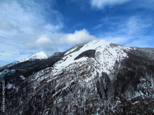 View of mountains Storzic and Srednji vrh in Kamnik-Savinja alps, Gorenjska, Slovenia in winter with white clouds on blue sky