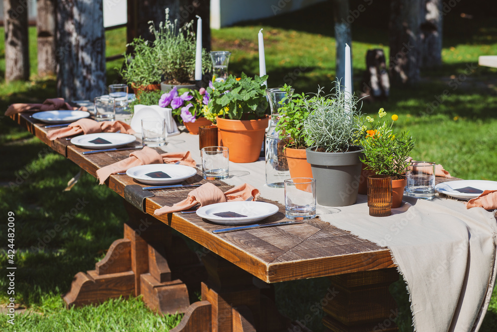 Banquet tables in nature. Wedding in the garden. Outdoor wedding. Buffet. Wedding banquet in nature.Festive table serving dishes stands on green grass. table compositions, glasses, candles and plates 