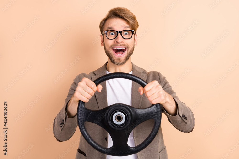 Fototapeta premium Photo of happy excited good mood crazy businessman riding car hold steering wheel isolated on beige color background