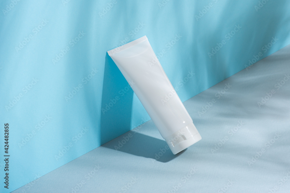 White plastic tube with face, hand and body cream on gray-blue paper. Sun protection lotion, sunscreen. Summer skincare concept with SPF Flat Lay. layout White plastic tube with face, hand and body cream on gray-blue paper. Sun protection lotion, sunscreen. Summer skincare concept with SPF Flat Lay. layout