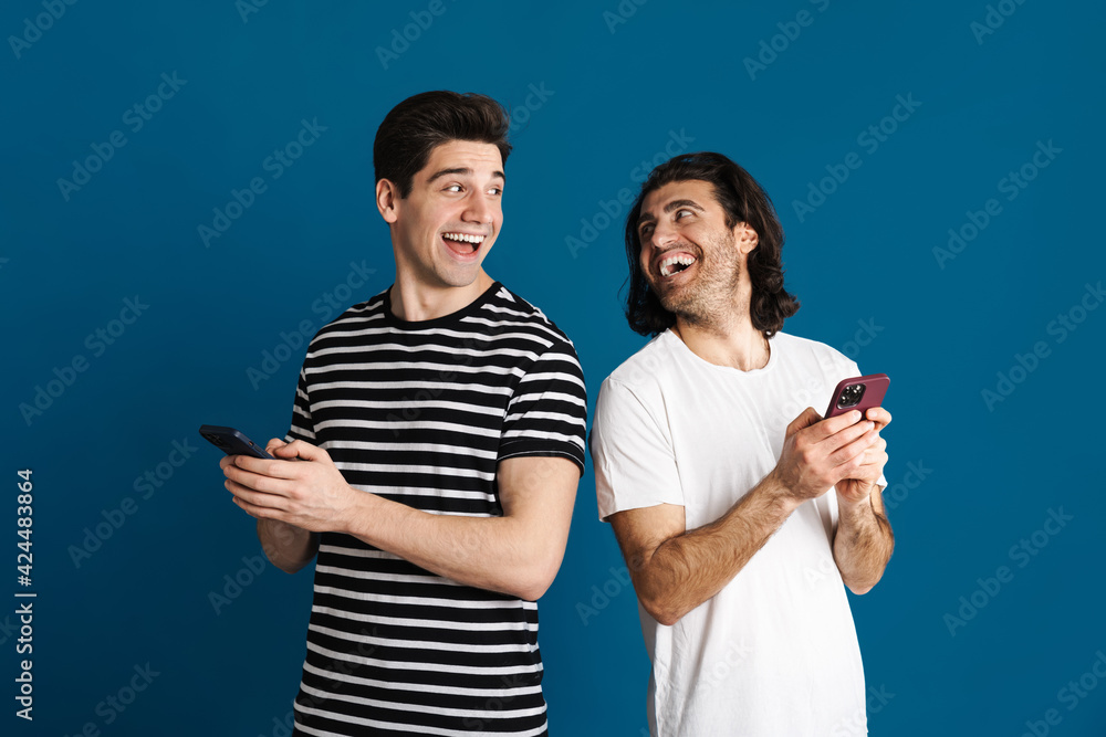 White happy two men laughing while using mobile phone White happy two men laughing while using mobile phone