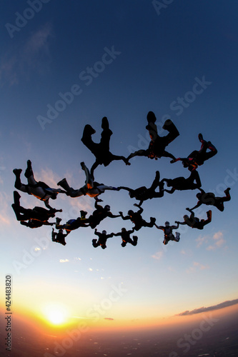 silhouette of skydive people flying in formation at sunset, adventure concept.