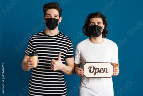 White brunette two men in face mask showing open sign board and thumb up