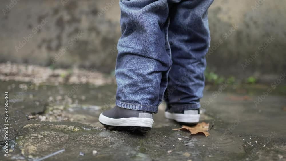 Child jumping into water puddle. Toddler wearing boots splash into puddle Child jumping into water puddle. Toddler wearing boots splash into puddle