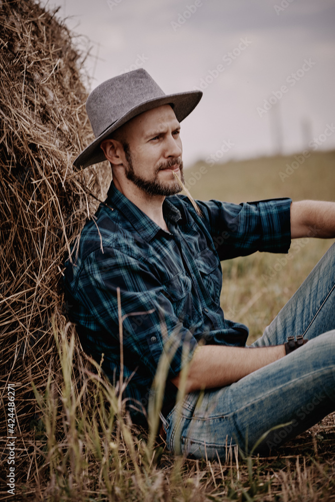 A man in a hat next to a haystack