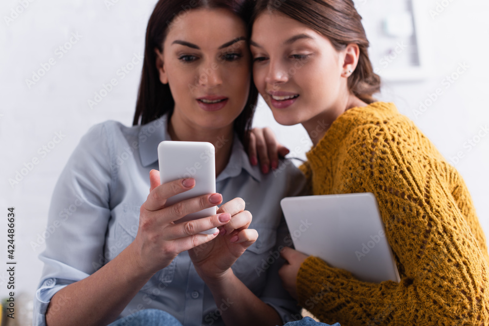 teenage girl holding digital tablet and looking at smartphone in mother hands teenage girl holding digital tablet and looking at smartphone in mother hands