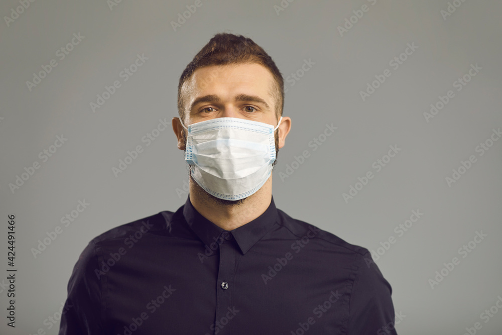 Portrait of serious caucasian man in face medical mask for protection from virus disease. Isolated headshot over on grey background. Protection against contagious coronavirus covid-19disease Portrait of serious caucasian man in face medical mask for protection from virus disease. Isolated headshot over on grey background. Protection against contagious coronavirus covid-19disease