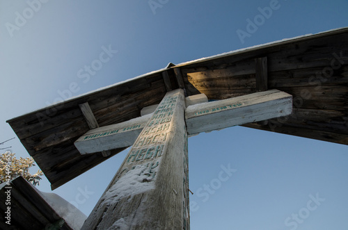 February 2021 - Kimzha. A venerated wooden antique cross with the image of Jesus and a prayer. Roadside cross. Russia, Arkhangelsk region, Mezensky district  photo