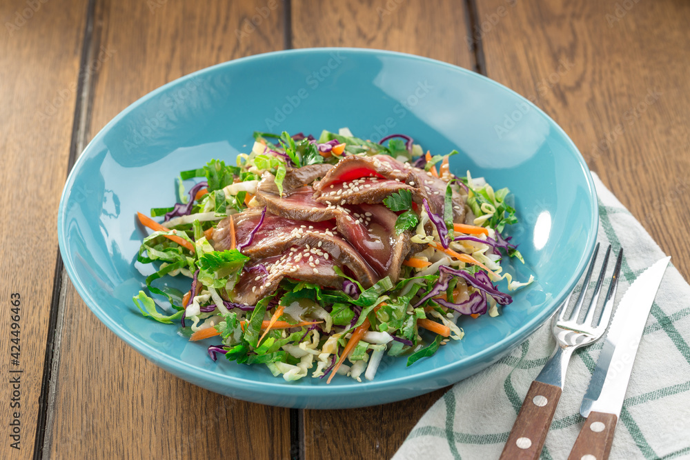 meat salad with roast beef, greens and sesame seeds asian style served on wooden table meat salad with roast beef, greens and sesame seeds asian style served on wooden table
