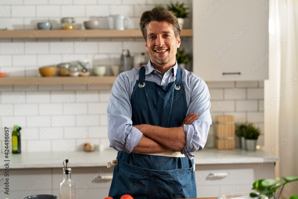 Happy man preparing food at home. Chef cooking tasty meal in kitchen.. Happy man preparing food at home. Chef cooking tasty meal in kitchen..