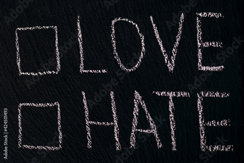 Writing in chalk on a rough board or asphalt love hate with checkmark option. The concept of choosing between love and hate in different spheres of life. Free space to choose where to tick photo