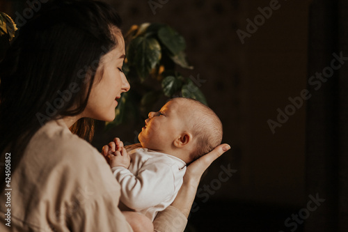 Fotografie, Obraz Loving mom carying of her newborn baby at home in evening