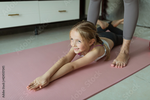 Little girl in sport clothing exercising at home. Online training during coronavirus covid-19 quarantine. Stay fit and safe during pandemic lockdown. Sport, fitness, healthy concept