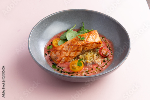 Salmon steak in a plate with sauce and vegetables.