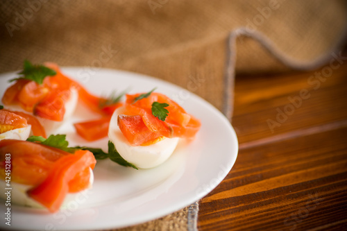 halves of boiled eggs with pieces of salted salmon