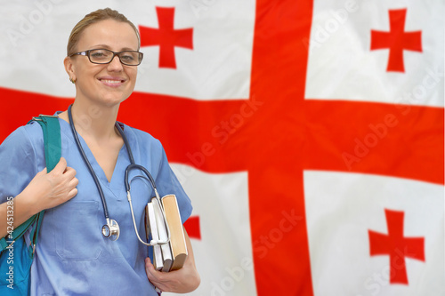 Woman intern doctor with stethoscope and books against Georgia flag background. Medical education in Georgia photo