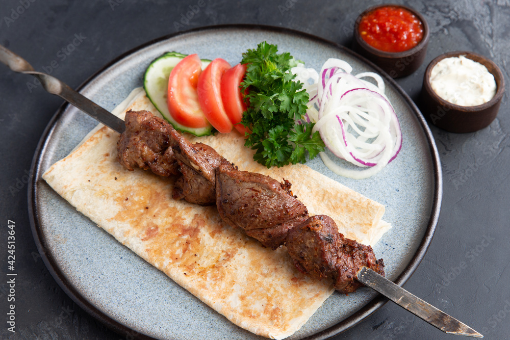 Lamb shashlik on a skewer in a plate.